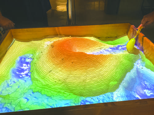 Graduate students Morgan Burke and Earl Klug working on the Augmented Reality Sandbox.