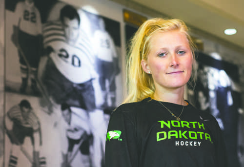 Lisa Marvin, a junior forward on the UND womens hockey team, stands in front of a mural dispaying her grandfather, Calvin Coolidge Marvin, who co-founded the mens hockey team.