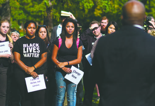 Selena Kibira (BLM shirt) and her friend Sade Lawal listen as Roy Roach speaks during the Zero-Tolerance rally outside Twamley Hall on Friday, September 30, 2016.