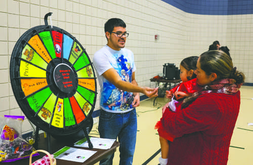 Christina Kissinger holds her daughter, Rosie, as UND student Marcus Vivier hands out candy at the UND India Association (UNDIA) Halloween carnival held Friday evening at the Wellness Center.