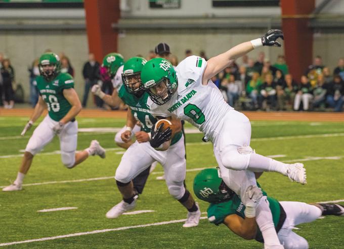 Cole Reyes (center) runs the ball during a green and white scrimmage last spring at the High Performance Center.