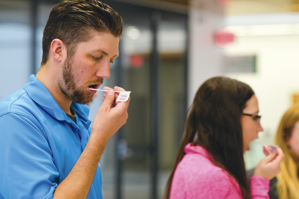 Paul Samson (left), medical lab science education specialist, and Shanalee Mountain (right), medical student, swab their mouths during a bone marrow volunteer drive on Wednesday, April 26, 2017 at the Medical School.