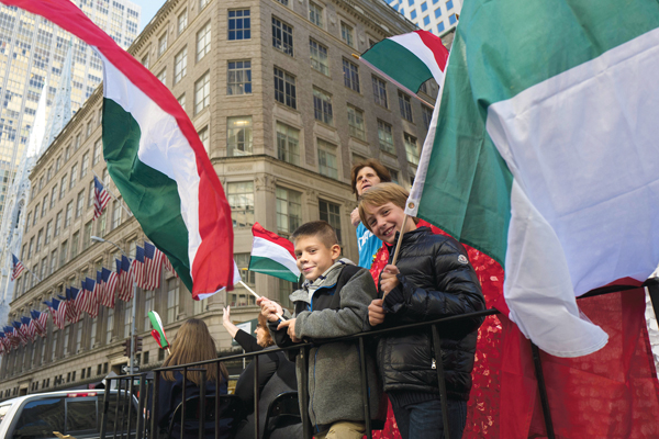 FILE- In this Oct. 10, 2016, file photo, boys wave Italian flags while riding a float in the Columbus Day Parade in New York. A movement to abolish Columbus Day and replace it with Indigenous Peoples' Day has new momentum but the gesture to recognize victims of European colonialism has also prompted howls of outrage from some Italian Americans, who say eliminating their festival of ethnic pride is culturally insensitive. (AP Photo/Mark Lennihan, File)