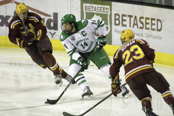 UND hockey captain Austin Poganski evades Minnesotas Ryan Lindgren (left) and Ryan Norman (right) during their matchup at the Ralph Engelstad Arena in October.