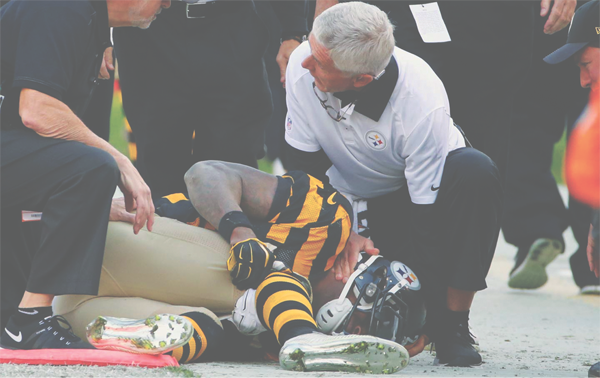 Pittsburgh Steelers running back Le'Veon Bell (26) holds his knee as Steelers' head trainer John Norwig tends to him after he was injured in the first half of an NFL football game against the Cincinnati Bengals, November 1, 2015 in Pittsburgh. 