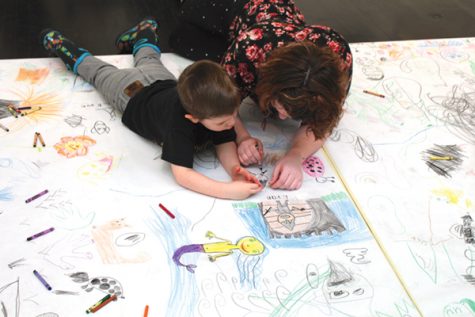 Liam Coons and his mother, Aimee, color on paper on the North Dakota Museum of Art gallery floor late Saturday morning. 