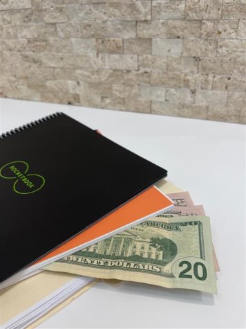 Money tucked into notebooks on white desk