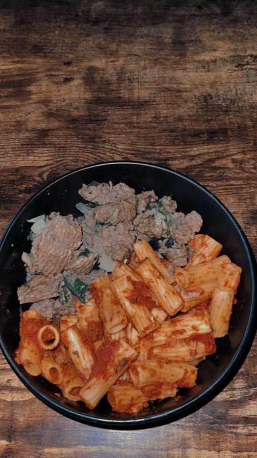 Bowl of pasta and meat on a table in a black bowl