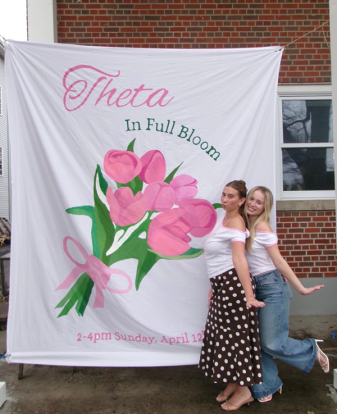Two sorority sisters take a picture in front of house.